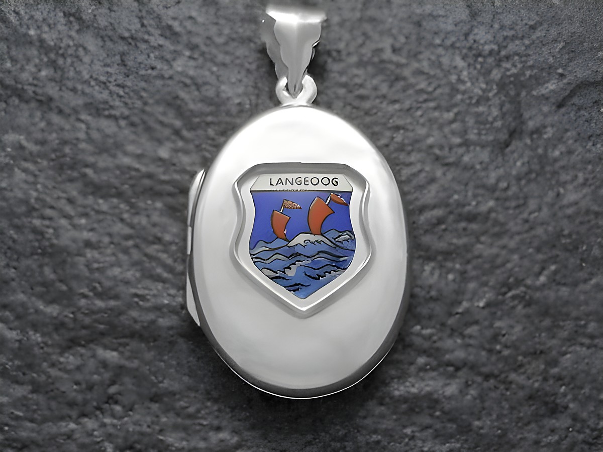 Das Bild zeigt ein silbernes Medaillon mit dem Wappen der Insel Langeoog, das einen blauen Hintergrund und rote Schiffe in bewegten Wellen darstellt, hergestellt von Juwelier Harnisch.