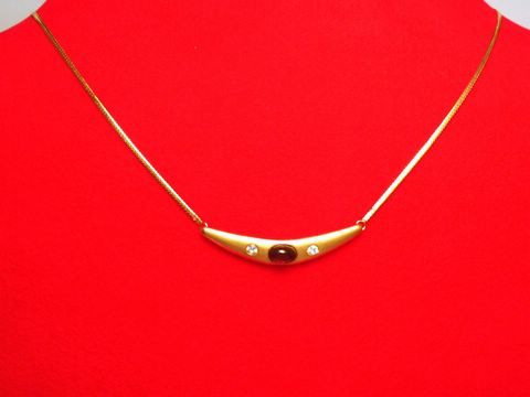 Collier Goldkette 333 mit einem Mittelteil aus Granat und Zirkonia, 41cm lang, gefertigt vom Juwelier Harnisch, präsentiert auf einem roten Untergrund.