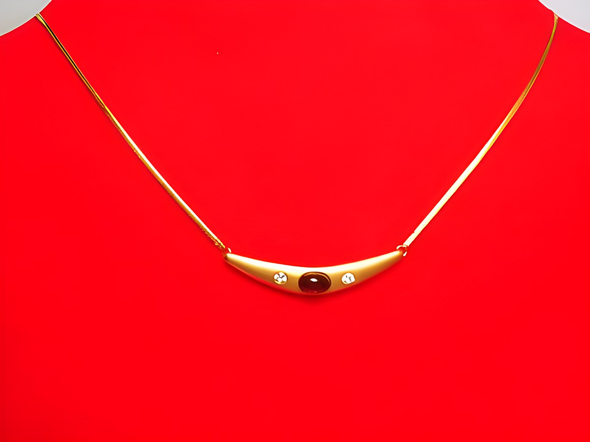 Collier Goldkette 333 mit einem Mittelteil aus Granat und Zirkonia, 41cm lang, gefertigt vom Juwelier Harnisch, präsentiert auf einem roten Untergrund.