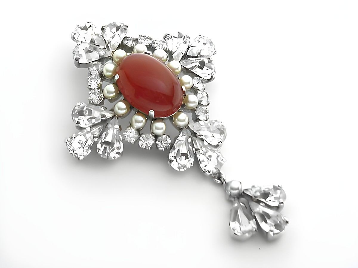 Königliche Strass Brosche mit einem roten Stein und weißen Strasssteinen in elegantem Design, Hersteller Juwelier Harnisch, ideal für einen sexy City Look.