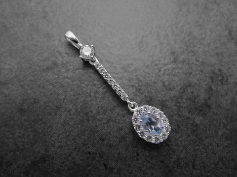Ovaler Anhänger aus Sterling Silber mit blauem Blautopas im Zentrum, umgeben von weißen Zirkonia, feines Design von Juwelier Harnisch, weitere Steine für zusätzlichen Glanz.