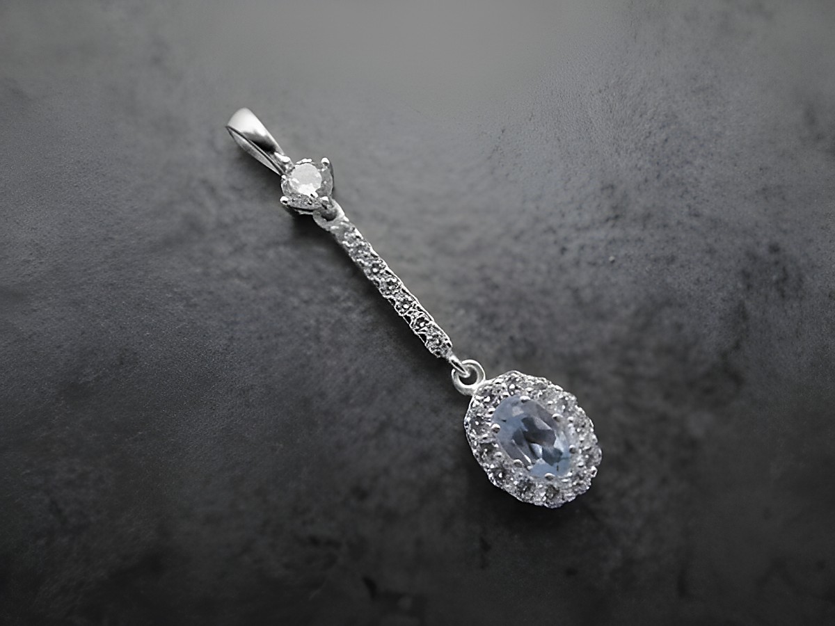 Ovaler Anhänger aus Sterling Silber mit blauem Blautopas im Zentrum, umgeben von weißen Zirkonia, feines Design von Juwelier Harnisch, weitere Steine für zusätzlichen Glanz.