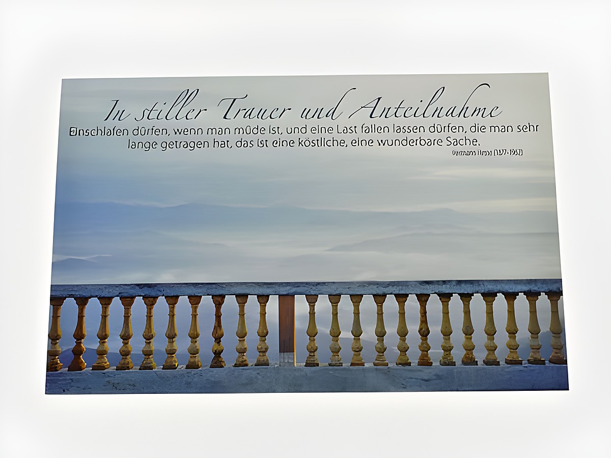 Eine Trauerkarte mit dem Titel "In stiller Trauer und Anteilnahme", die in sanften Blau- und Grautönen gehalten ist. Im Hintergrund ist eine Landschaft mit einem Geländer zu sehen und eine ruhige, melancholische Atmosphäre vermittelt.
