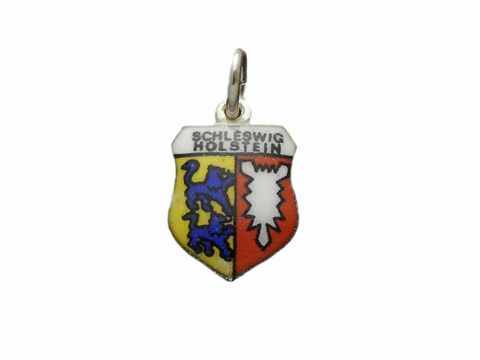 Silberner Anhänger mit dem Wappen von Schleswig-Holstein, farblich gestaltet mit gelbem, blauem und rotem Schild sowie dem Schriftzug Schleswig-Holstein, hergestellt von Juwelier Harnisch.