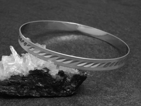 Silber Armreifen modern 6,4 mm rhodiniert 20 cm von Juwelier Harnisch, gefertigt aus glänzendem Silber mit dekorativen Aussparungen, elegant auf einem dunklen Untergrund präsentiert.