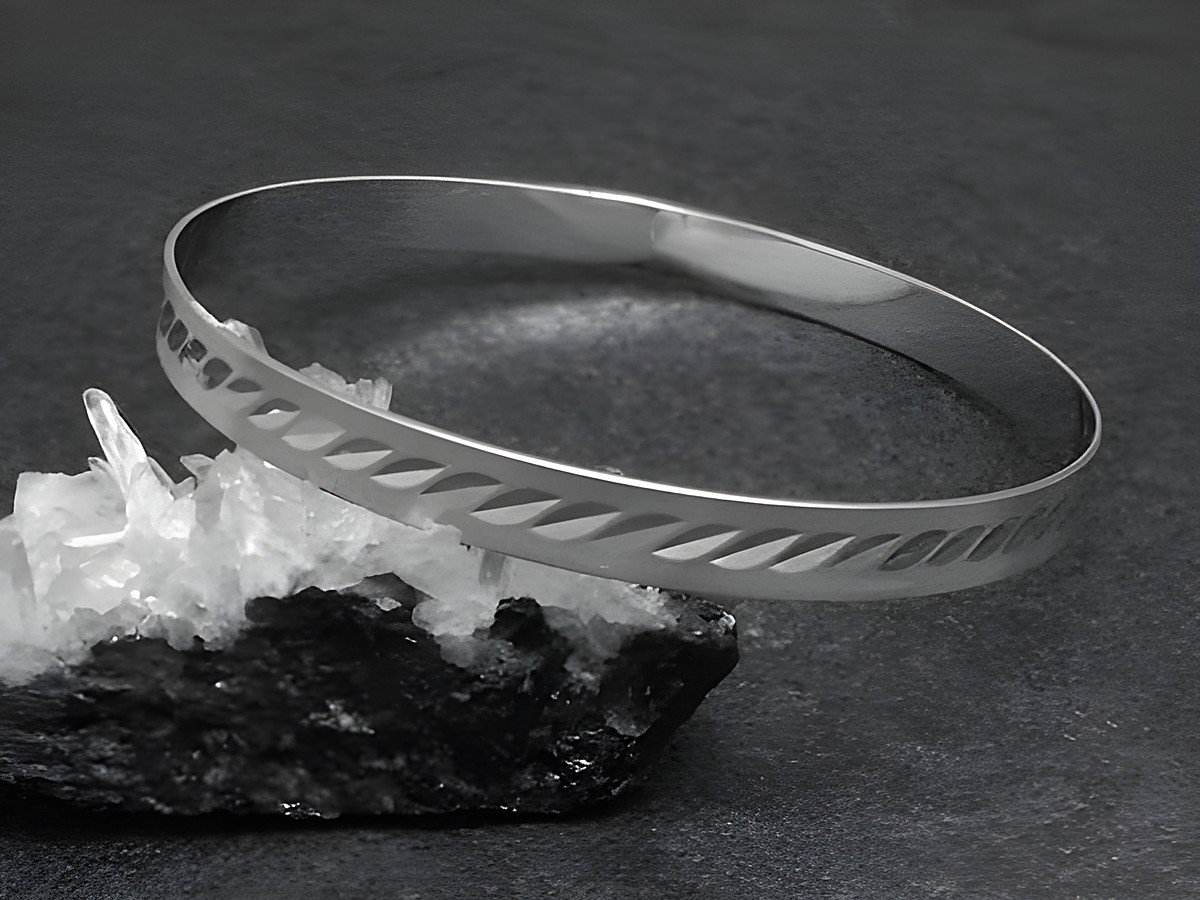 Silber Armreifen modern 6,4 mm rhodiniert 20 cm von Juwelier Harnisch, gefertigt aus glänzendem Silber mit dekorativen Aussparungen, elegant auf einem dunklen Untergrund präsentiert.