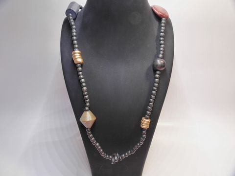 61739-0 Holzkette Multiform 24 mm bunt 90 cm Holz Schmuck vom Hersteller Juwelier Harnisch zeigt eine bunte Kette mit verschiedenen Holzperlen und Formen auf einem Schmuckständer.