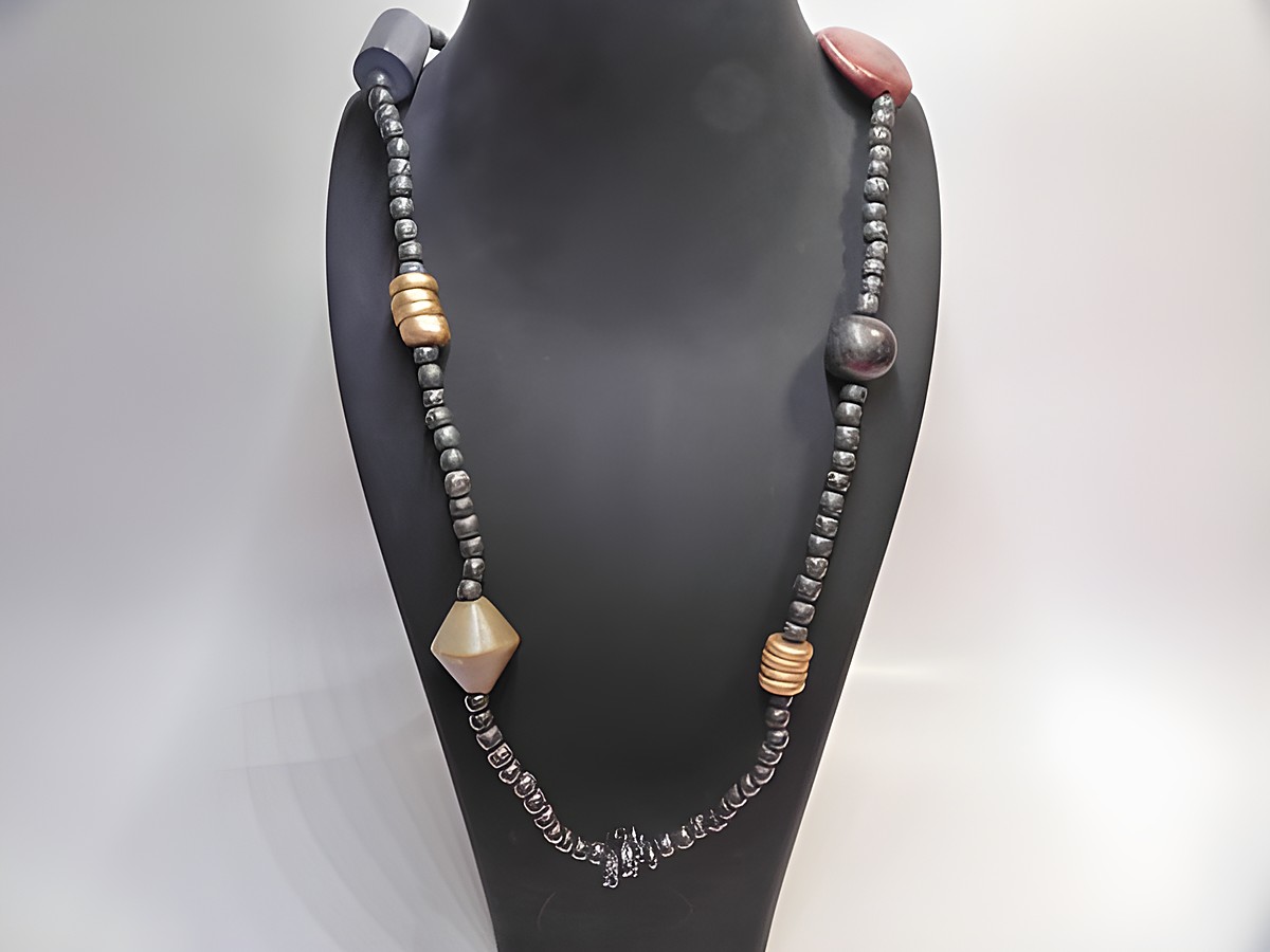 Holzkette Multiform 24 mm bunt 90 cm Holz Schmuck vom Hersteller Juwelier Harnisch zeigt eine bunte Kette mit verschiedenen Holzperlen und Formen auf einem Schmuckständer.