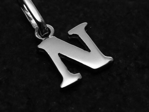 Ein Anhänger in Form des Buchstabens N aus Weißgold 585, hergestellt von Juwelier Harnisch. Der Buchstabe ist elegant und glänzend auf schwarzem Hintergrund präsentiert.