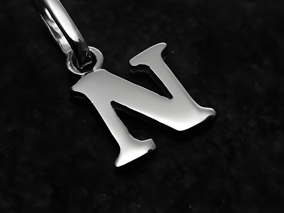 Ein Anhänger in Form des Buchstabens N aus Weißgold 585, hergestellt von Juwelier Harnisch. Der Buchstabe ist elegant und glänzend auf schwarzem Hintergrund präsentiert.