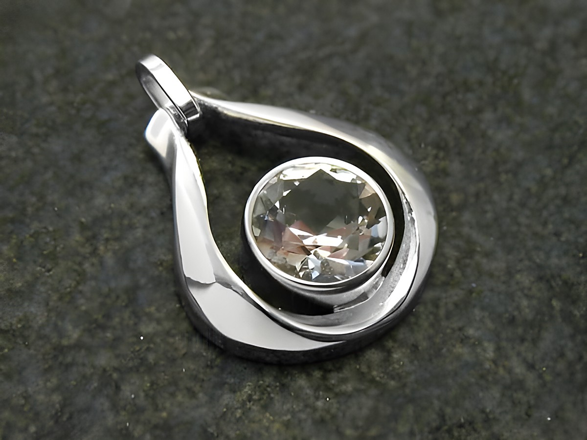 Designer Goldanhänger aus 18 mm Weißgold mit einem zentralen Bergkristall. Der Anhänger hat eine elegante Tropfenform und glänzende Oberflächen, ideal für modebewusste Träger.