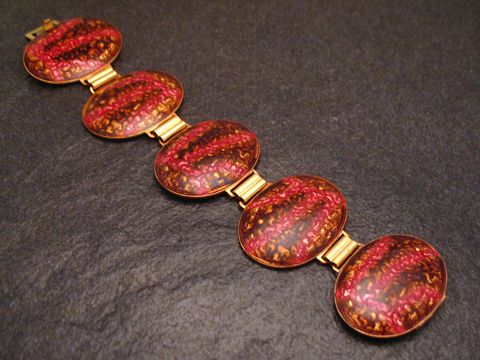 60964-0 Armband 19 cm MIX-IT braun-pink - Emaille vergoldet, von Juwelier Harnisch, zeigt eine elegante Anordnung von ovalen Emaille-Elementen in warmen Farben auf einem dunklen Untergrund.