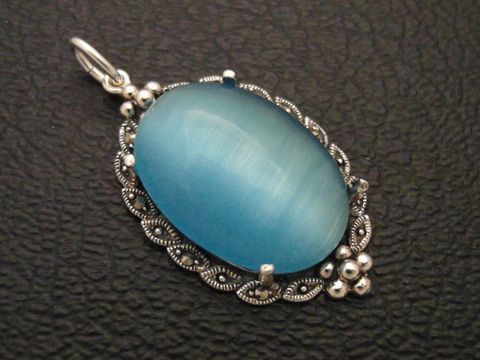 Silber Medaillon Anhänger mit Cabochon Katzenauge in türkisblau, gefertigt von Juwelier Harnisch, elegant und stilvoll, ideal als Schmuckstück für jeden Anlass.
