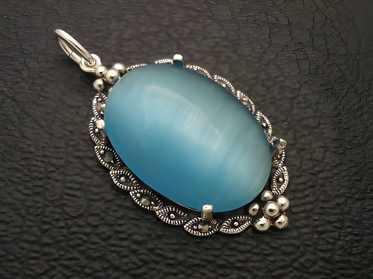 Silber Medaillon Anhänger mit Cabochon Katzenauge in türkisblau, gefertigt von Juwelier Harnisch, elegant und stilvoll, ideal als Schmuckstück für jeden Anlass.