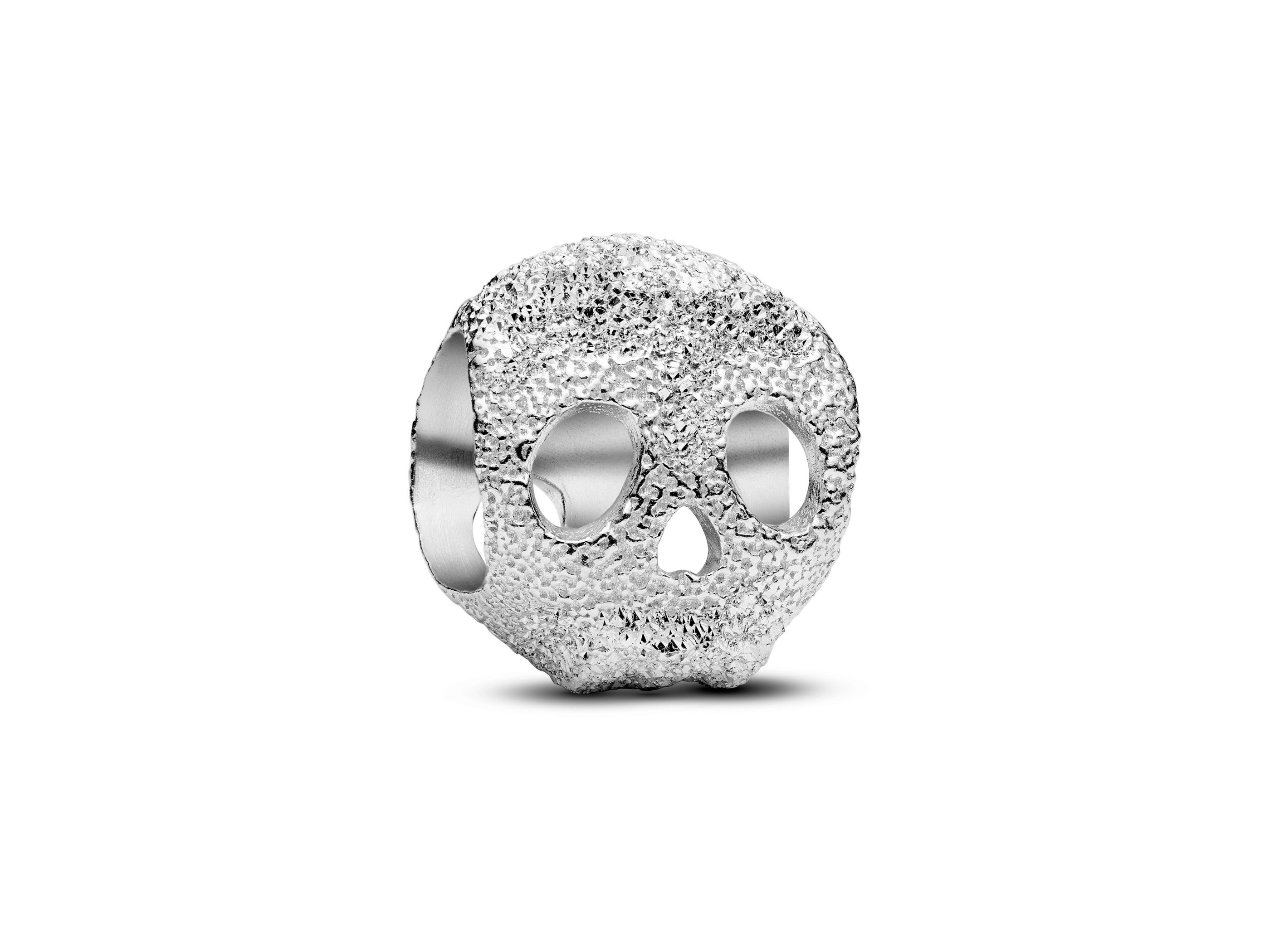 Der strukturierte Totenkopf Mini-Charm aus Sterling Silber von Pandora zeigt einen detailliert gestalteten, glänzenden Totenkopf mit deutlich sichtbaren Augen- und Nasenausschnitten.