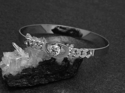 Silber Armreifen pompös 8,1 mm rhodiniert 17 cm von Juwelier Harnisch mit funkelndem Stein auf schwarzem Hintergrund und Kristallen. Ideal für elegante Anlässe.