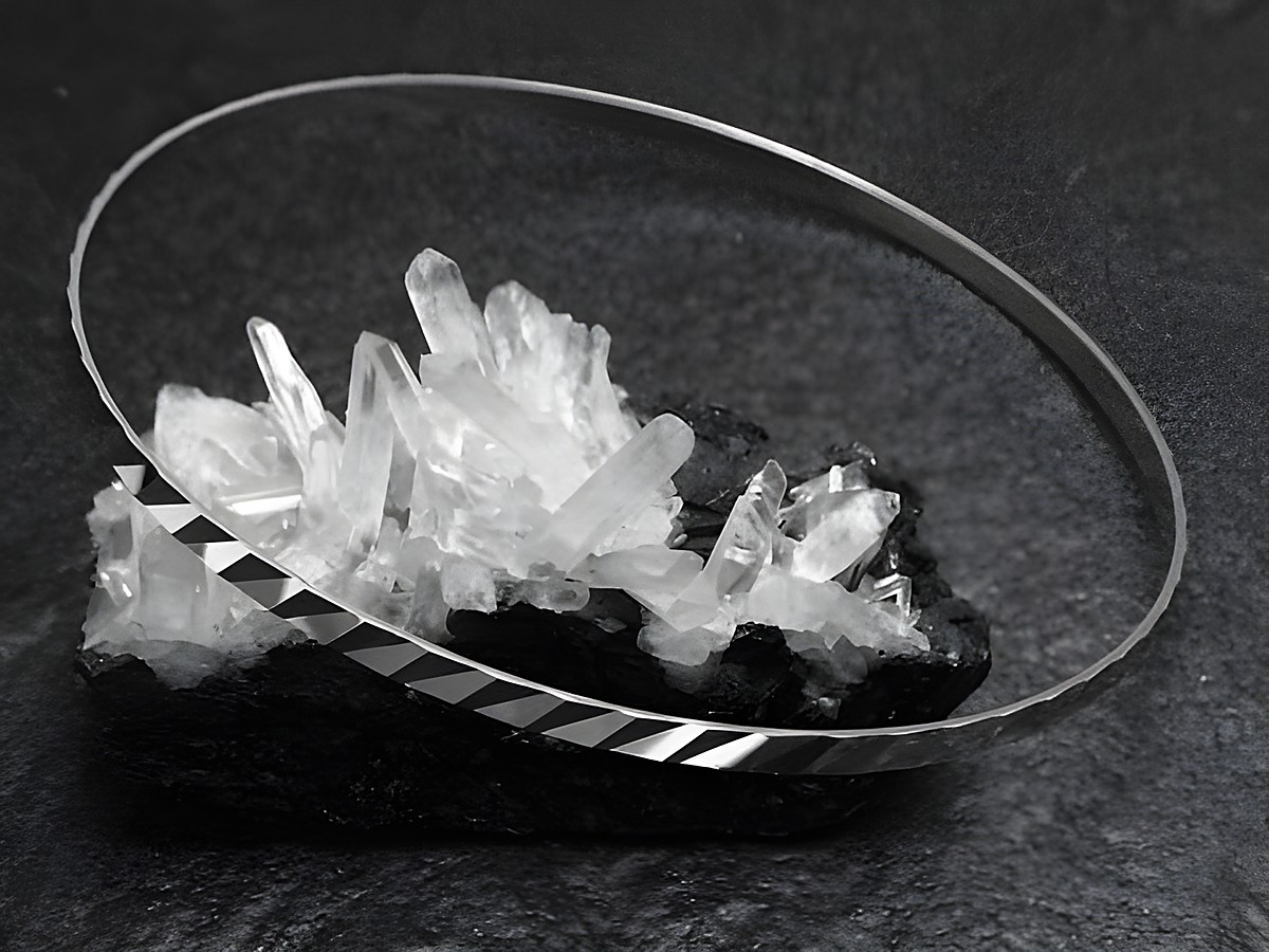 Silber Armreifen rhodiniert im 70er Schliff, 2,5 mm dick, 21 cm lang, hergestellt von Juwelier Harnisch, elegant präsentiert auf einer Kristallbasis.
