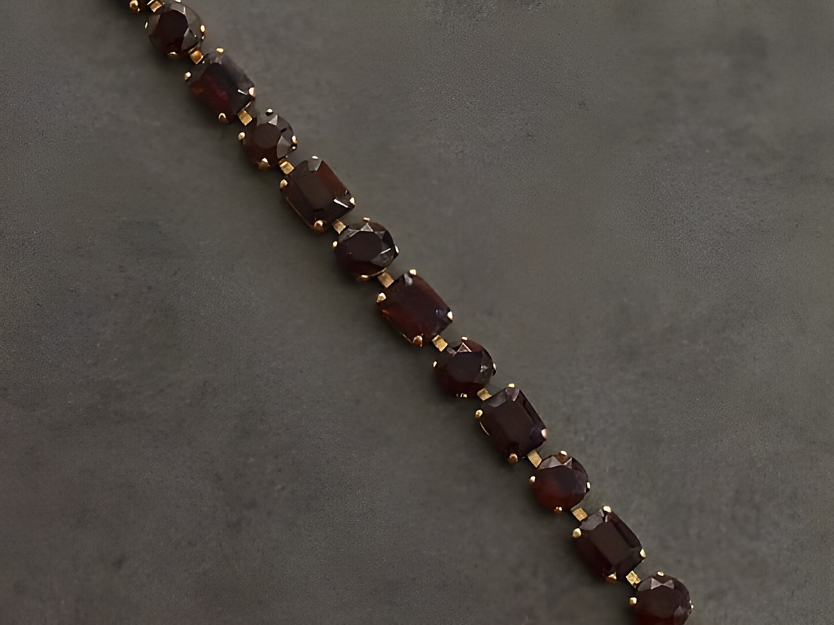 Ein elegantes Strass Armband in granatrot mit goldfarbenen Details, 19 cm lang, hergestellt von Juwelier Harnisch, ideal für stilvolle Anlässe.