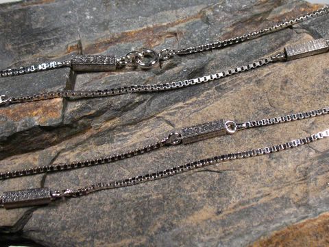 Lange Silberkette Venezia mit eckigen Elementen rhodiniert, 87 cm, Hersteller Juwelier Harnisch, sichtbare Mittelteile für Colliers auf grauem Steinuntergrund.