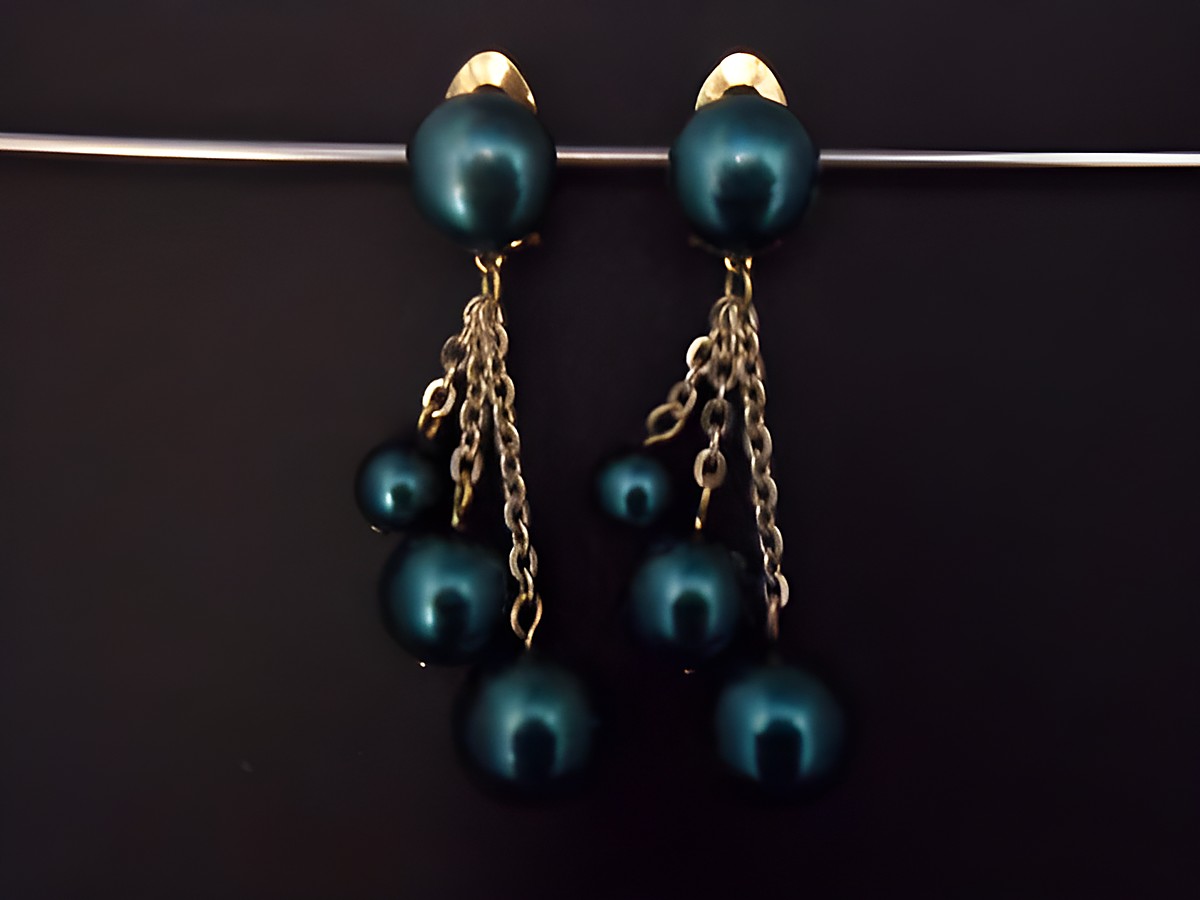Dunkelgrüne Ohrclips aus Kunstharz mit goldfarbenen Elementen, elegantes Design mit hängenden Perlen in verschiedenen Größen, Hersteller Juwelier Harnisch.