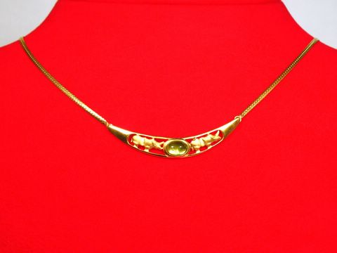 Collier aus Gold 333 mit Mittelteil in Form eines Nashorns und Turmalin, Länge 42,5 cm, Hersteller Juwelier Harnisch, elegantes Design auf rotem Hintergrund.