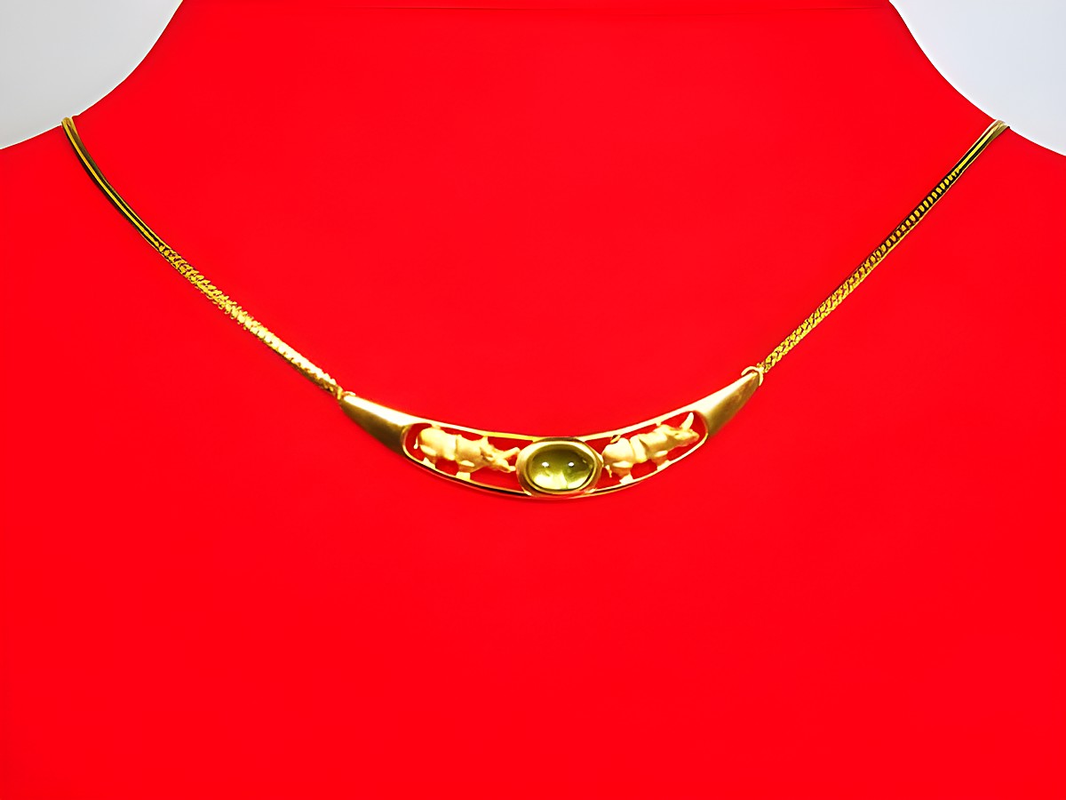 Collier aus Gold 333 mit Mittelteil in Form eines Nashorns und Turmalin, Länge 42,5 cm, Hersteller Juwelier Harnisch, elegantes Design auf rotem Hintergrund.