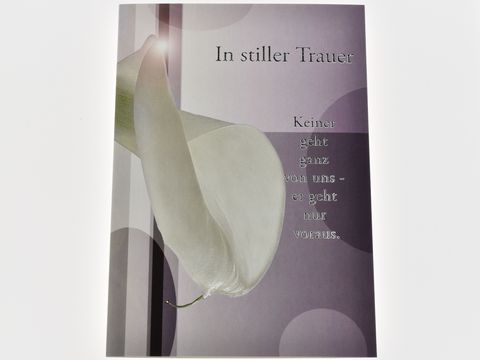 Eine Trauerkarte mit einer weißen Blüte im Vordergrund und einem sanften, minimalistischen Hintergrund. Der Text beschreibt den Verlust und die Trauer. Hersteller Juwelier Harnisch.