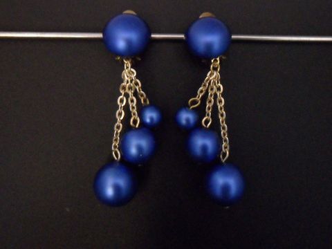 Ohrclip in zeitlosem Design, blau und goldfarben, aus seidenmattem Kunstharz, Hersteller Juwelier Harnisch, mit eleganten Ketten und verschiedenen blauen Perlen.