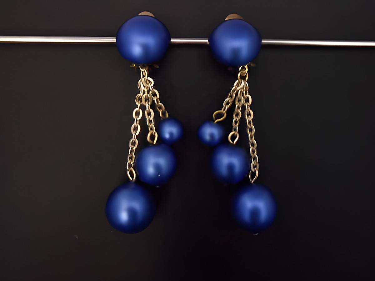 Ohrclip in zeitlosem Design, blau und goldfarben, aus seidenmattem Kunstharz, Hersteller Juwelier Harnisch, mit eleganten Ketten und verschiedenen blauen Perlen.