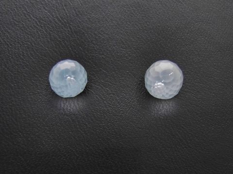 Zwei facettierte Blautopas Ohrstecker aus Sterling Silber in Kugel-Design, hergestellt von Juwelier Harnisch, auf schwarzem Hintergrund platziert.
