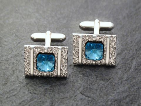 Silberfarbene Manschettenknöpfe mit rhodinierten Strass-Steinen in blauer Farbe, hergestellt vom Juwelier Harnisch, elegant und stilvoll für besondere Anlässe.
