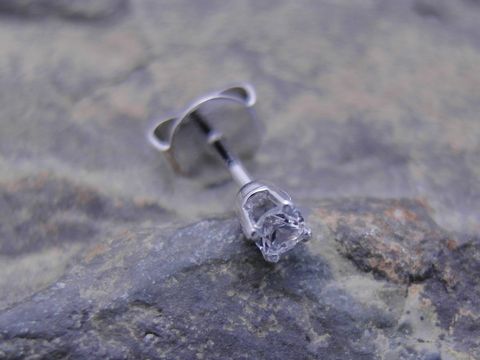 Ein einzelner unisex Ohrstecker aus Weißgold 585 mit einem traumhaften Zirkonia, Hersteller Juwelier Harnisch, auf einer steinernen Unterlage.