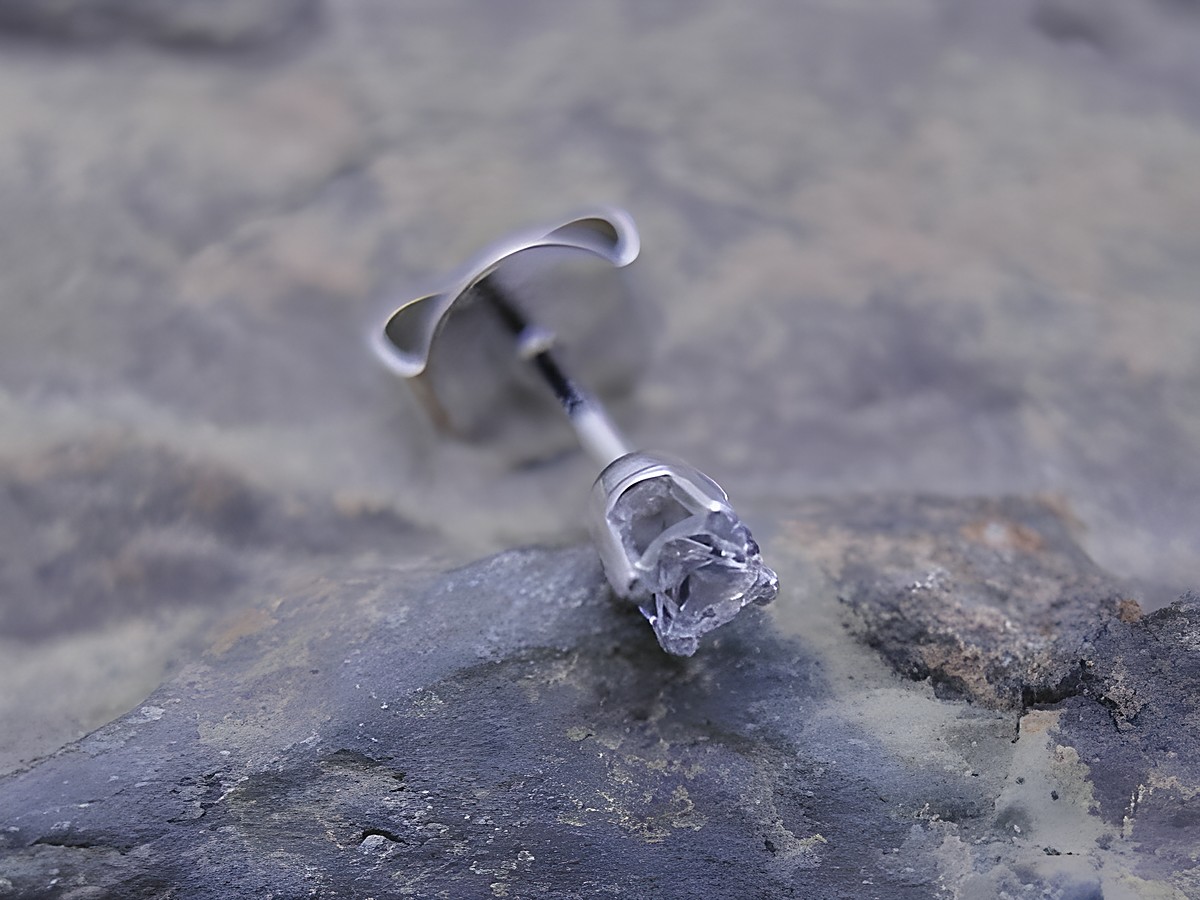 Ein einzelner unisex Ohrstecker aus Weißgold 585 mit einem traumhaften Zirkonia, Hersteller Juwelier Harnisch, auf einer steinernen Unterlage.