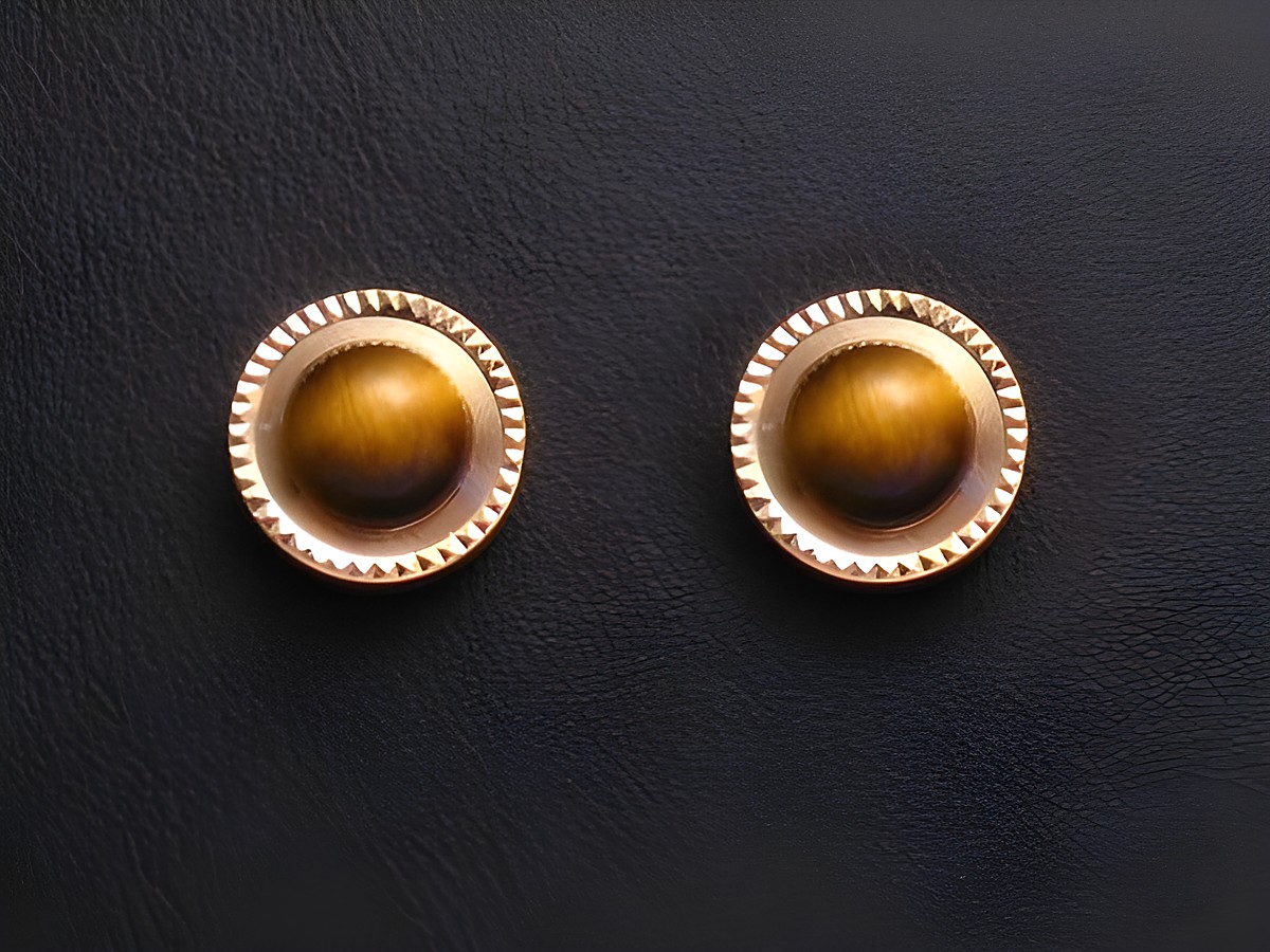 Ohrringe aus Tigerauge mit goldenen Ohrsteckern, Hersteller Juwelier Harnisch, verziert mit weiteren Steinen, elegantes Design auf schwarzem Hintergrund.