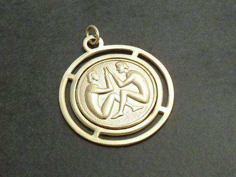 Goldfarbene, runde 3D-Platte mit dem Sternzeichen Zwillinge, dargestellt durch zwei sitzende Figuren. Hergestellt von Juwelier Harnisch, ideal als Schmuckstück für Sternzeichen-Liebhaber.