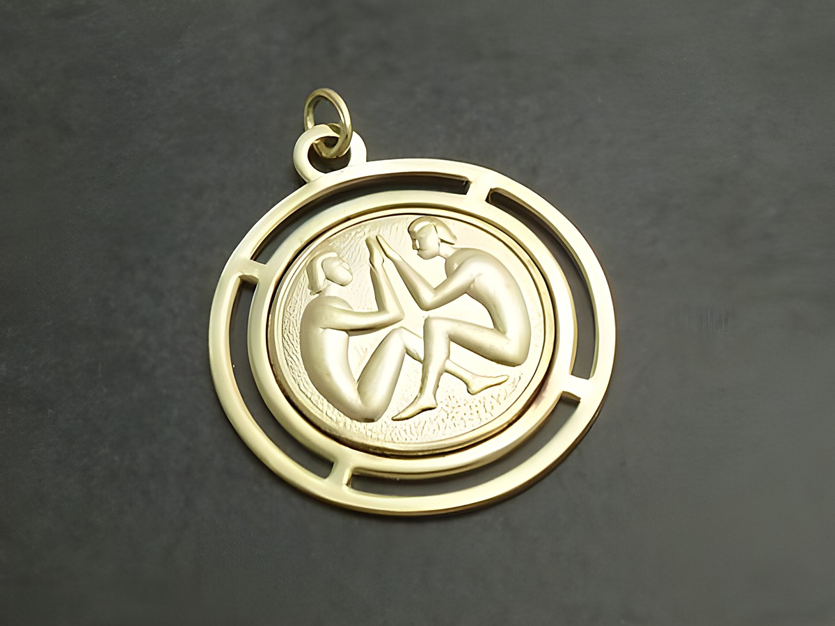 Goldfarbene, runde 3D-Platte mit dem Sternzeichen Zwillinge, dargestellt durch zwei sitzende Figuren. Hergestellt von Juwelier Harnisch, ideal als Schmuckstück für Sternzeichen-Liebhaber.