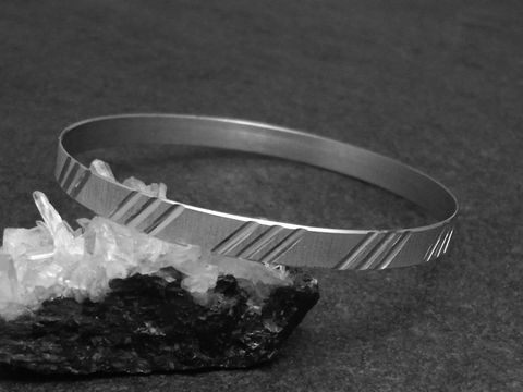 Silber Armreifen cultig 6,1 mm rhodiniert 20 cm von Juwelier Harnisch auf schwarzem Untergrund mit klaren Kristallen im Vordergrund abgebildet. Elegantes und modernes Design.