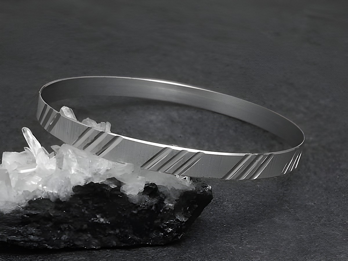Silber Armreifen cultig 6,1 mm rhodiniert 20 cm von Juwelier Harnisch auf schwarzem Untergrund mit klaren Kristallen im Vordergrund abgebildet. Elegantes und modernes Design.