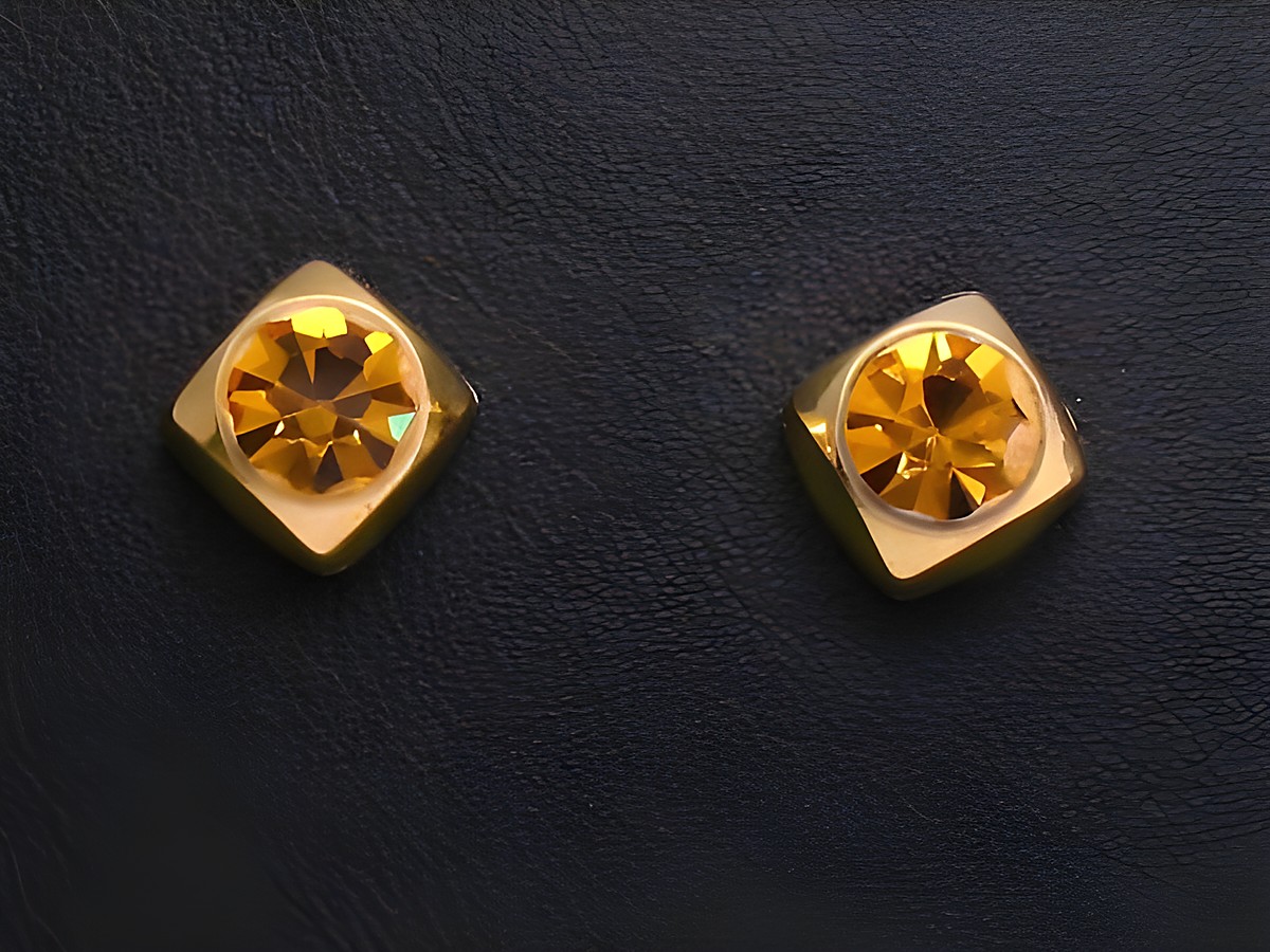 Zwei facettierte Citrin Ohrstecker in Goldfassung vom Juwelier Harnisch, mit schimmernden Details und modernen Design, ideal für elegante Anlässe.