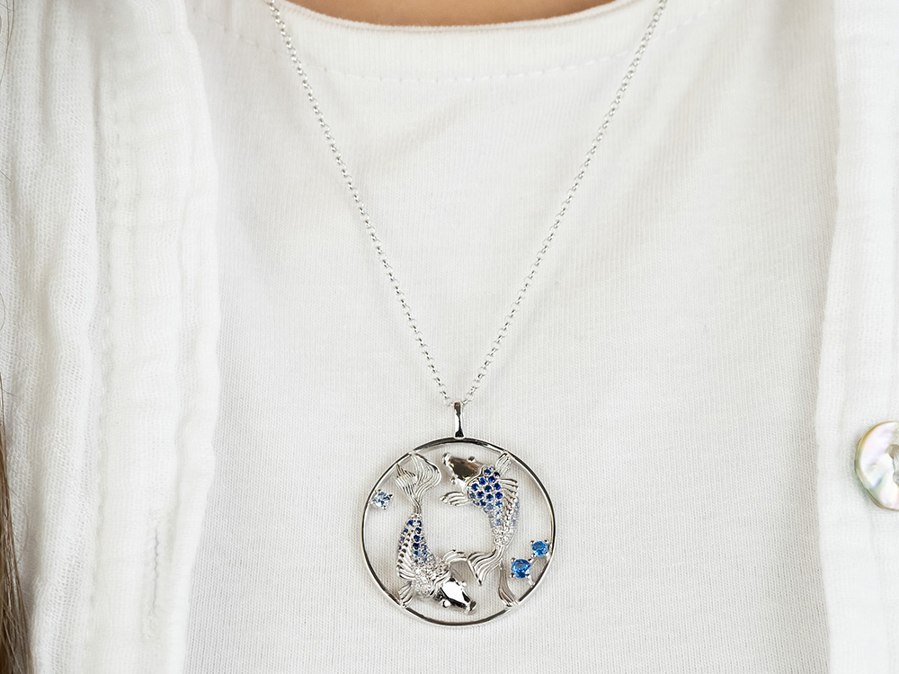 Silberne Yin Yang Kette mit Fischen und Zirkonia, präsentiert an einer weißen Bluse, symbolisiert Harmonie und Balance, von der Marke Engelsrufer.