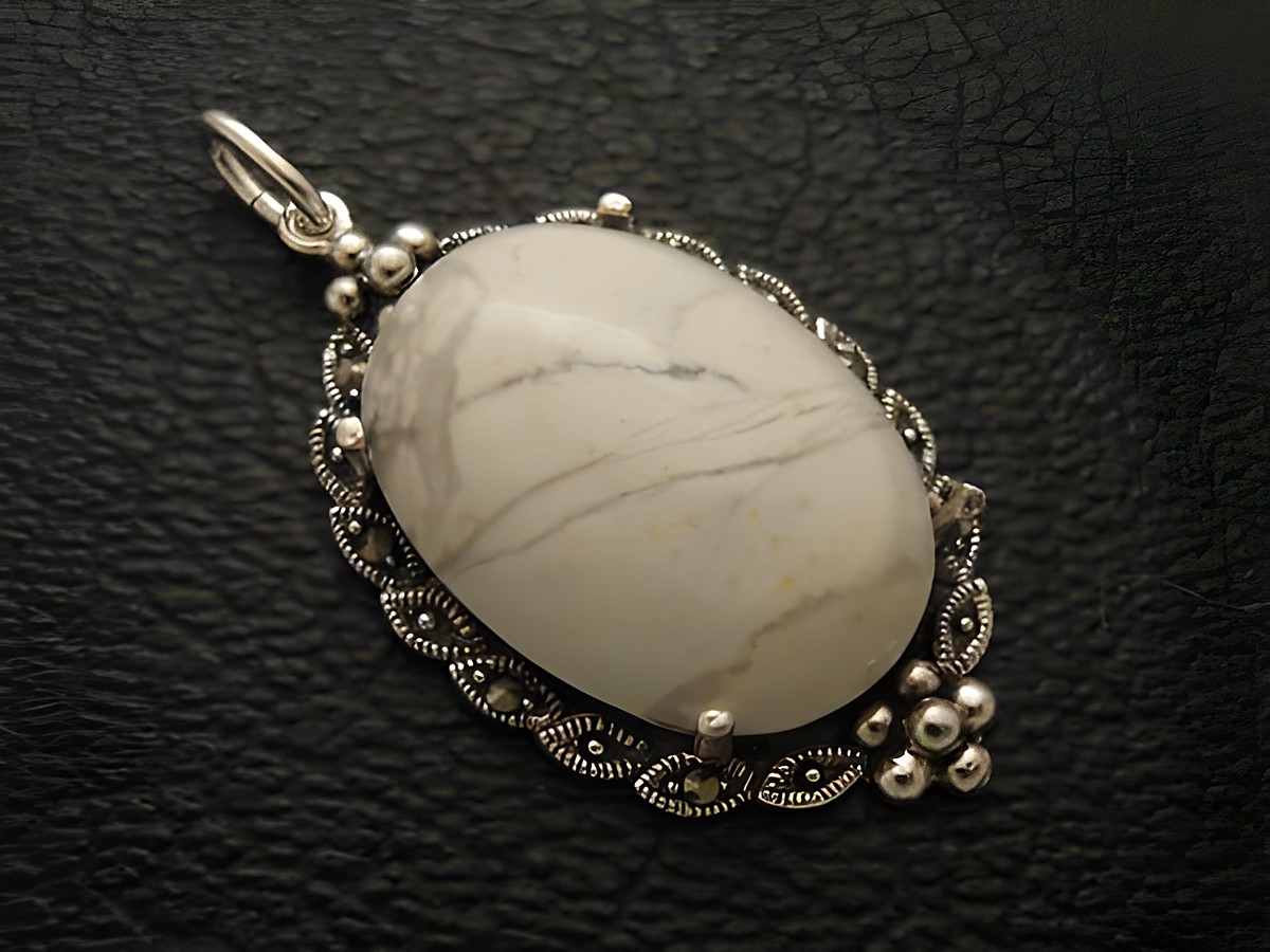Cabochon aus Howlith in Weiß, eingefasst in Silber als Medaillon Anhänger, Hersteller Juwelier Harnisch, elegantes Design mit feinen Details.