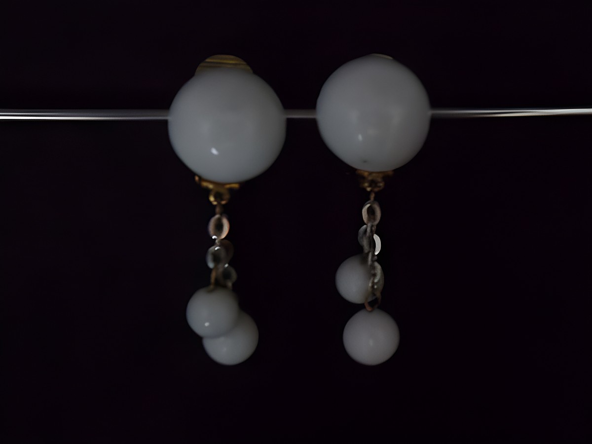Ohrclip in sommerweiß und zeitlosem Design, goldfarbene Details, gefertigt aus Kunstharz, Hersteller Juwelier Harnisch, mit hängenden Elementen und rundem Hauptteil.