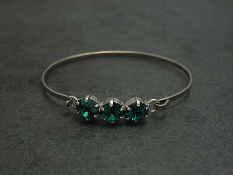 Dunkelgrüner Strass Armreifen mit drei funkelnden Steinen, 18 cm lang, silberfarbener Metallrahmen, feminin, Hersteller Juwelier Harnisch. Ideal für elegante Anlässe.