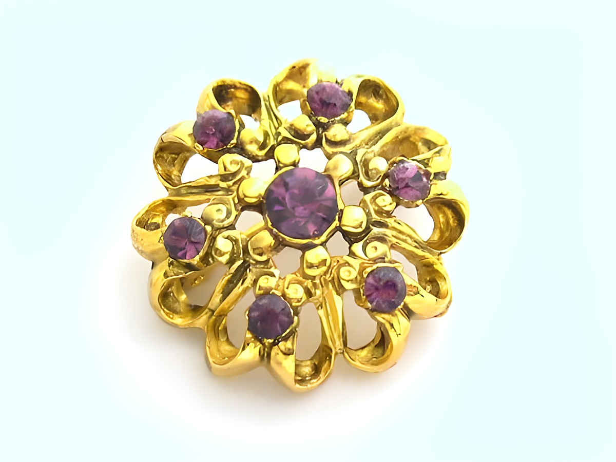 Lila Strass Brosche im Sexy City Look mit runden lila Strasssteinen und geschwungenem Golddesign, Hersteller Juwelier Harnisch. Ideal als elegantes Accessoire.