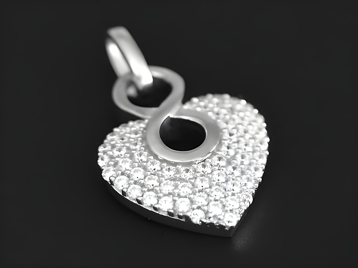 Ein rhodinierter Silberanhänger in Herzform mit einem unendlichen Zeichen, besetzt mit Zirkonia, symbolisiert ewige Liebe, hergestellt von Juwelier Harnisch, Perlen & Steine.