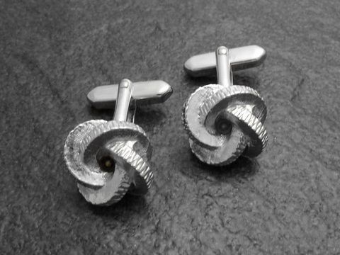 10007-0 Manschettenknöpfe silberfarben im Design einer Knotenform, Hersteller Juwelier Harnisch, goldfarbenes Detail, elegant und stilvoll, ideal für besondere Anlässe.