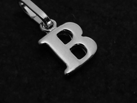 Buchstaben Anhänger in Form des Buchstabens B aus Weißgold 585 vom Hersteller Juwelier Harnisch, glänzende Oberfläche auf schwarzem Hintergrund.