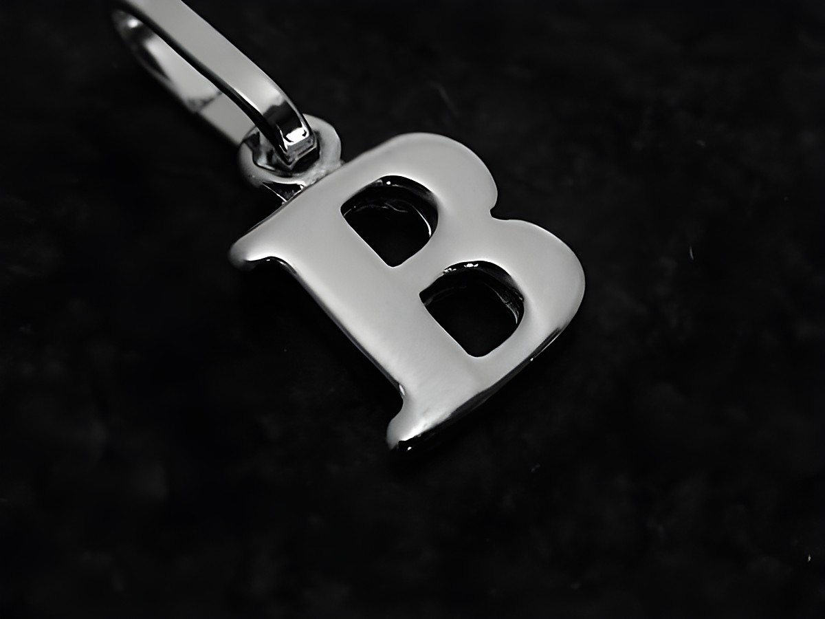 Buchstaben Anhänger in Form des Buchstabens B aus Weißgold 585 vom Hersteller Juwelier Harnisch, glänzende Oberfläche auf schwarzem Hintergrund.