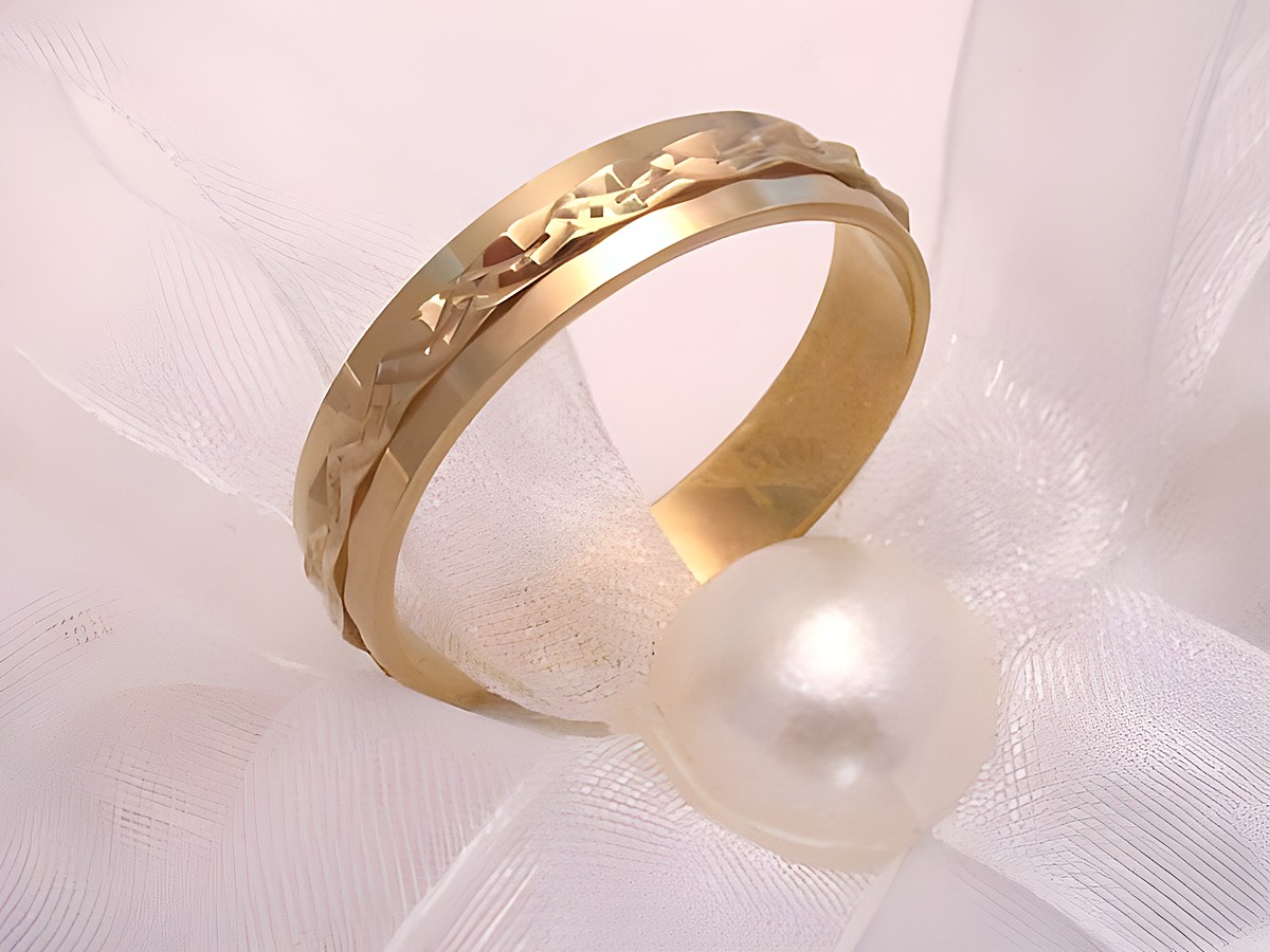 Trauring Ehering LIVELY aus Gold 333 in Größe 64/20,4 mit einem dekorativen Design, liegend auf zarter, transparenter Stoffoberfläche neben einer Perle. Hersteller: Juwelier Harnisch.