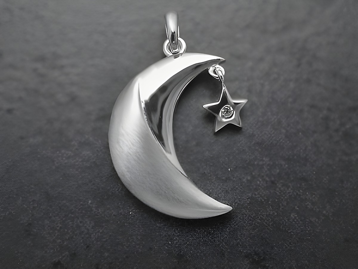 Anhänger aus sterling Silber in Form eines Mondes mit einem hängenden Stern, teilmattiert und mit Zirkonia verziert, hergestellt vom Juwelier Harnisch, Design Sonne Mond Sterne.